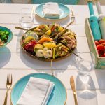 A beautifully arranged seafood platter and fresh salad on an outdoor patio table set for dining.