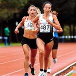 Young sportswomen in active wear with numbers running while participating in track and field athletics competition